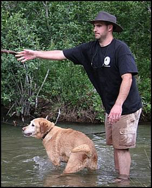 Mark Jablin playing with dog in stream